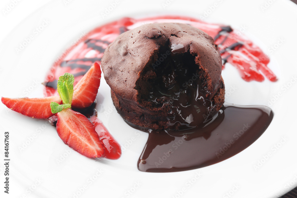 Chocolate fondant with strawberries on white plate, closeup