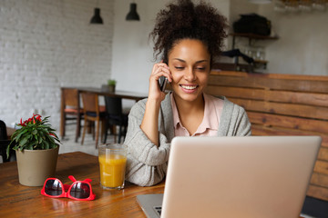 Young woman using mobile phone and working on laptop