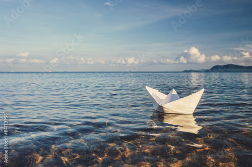 Fotografia origami paper sailboat sailing on blue water