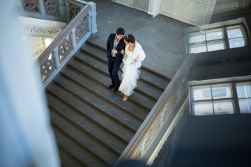 Wall Mural - Fancy wedding couple holding hands walking the stairs down