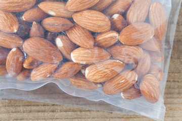 Almond in plastic bag on wood table background