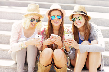 Wall Mural - Group of friends using smartphones in the city