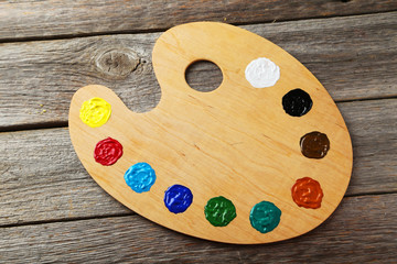 Wooden art palette with paints on grey wooden background