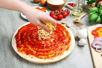 Wall Mural - Woman making pizza on table close up