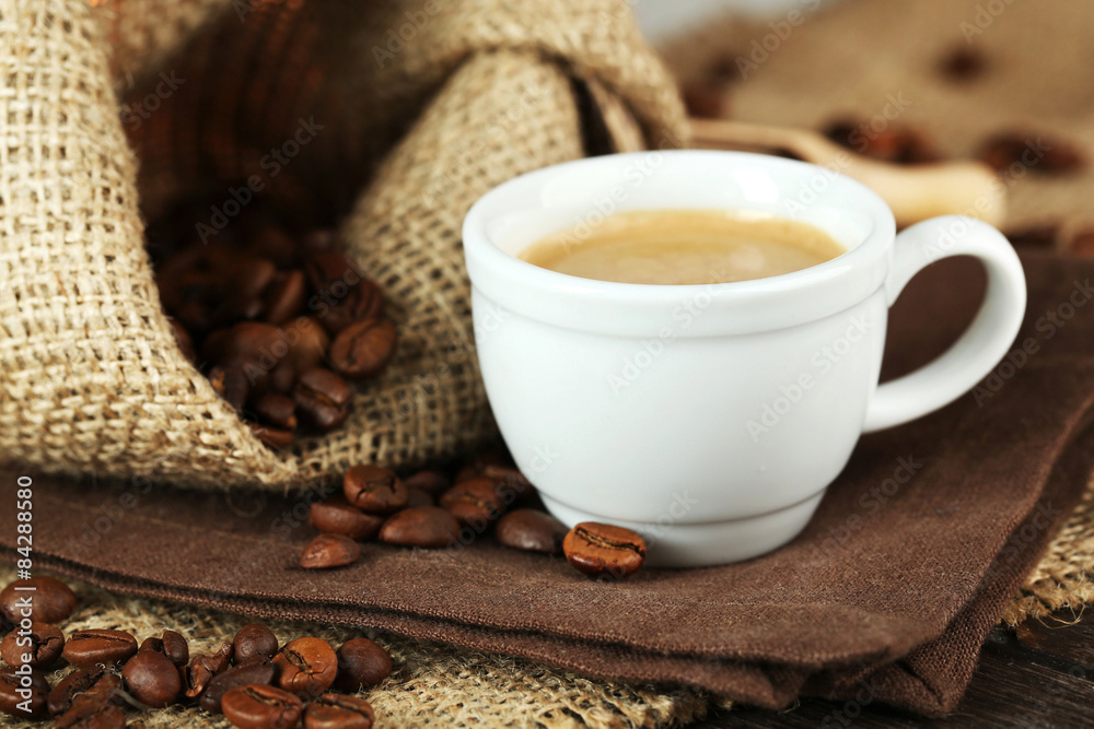 Cup of coffee with beans on table close up