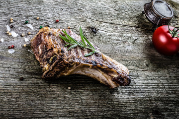 Pork steak with rosemary and pepper on old wooden table. Toned