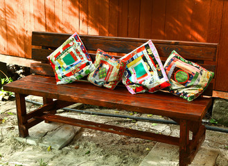 beautiful patch work pillows on the wooden bench