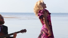Guitarist Plays And Blonde Girl Dances On Beach At Low Tide	