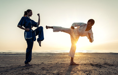 couple training in martial arts on the beach