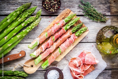 Fotografía Fresh organic asparagus wrapped in Parma ham on a cutting board
