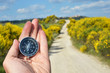 Compass in the hand against rural road