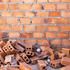 Canvas Print - pile of bricks in construction site with brick wall background