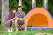 © bokan - Happy young couple sitting in front of the tent while camping in a forest