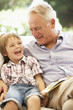 © Monkey Business - Grandfather With Grandson Reading Together On Sofa
