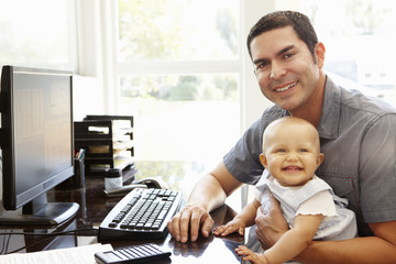 Wall Mural - Hispanic father with baby working in home office