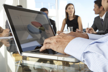 Wall Mural - Close Up Of Businessman Using Laptop During Board Meeting Around Glass Table