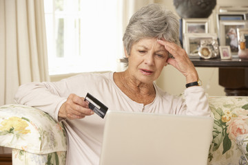 Wall Mural - Frustrated Retired Senior Woman Sitting On Sofa At Home Using Laptop