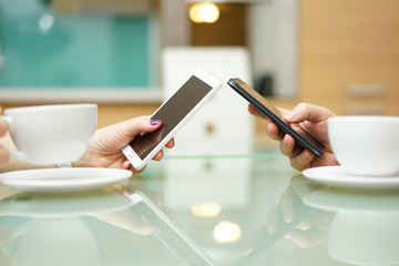 young couple in kitchen drinking coffee and using smart mobile p