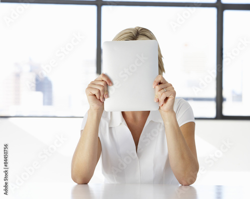 Fotografía Businesswoman Sitting At Desk In Office With Face Hidden Behind Digital Tablet