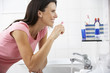 © Monkey Business - Woman In Bathroom Brushing Teeth
