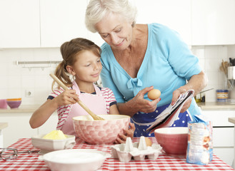 Grandmother And Granddaughter Baking In Kitchen