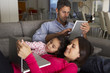 © Monkey Business - Hispanic Family On Sofa Using Laptop And Digital Tablet