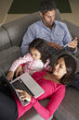 © Monkey Business - Hispanic Family On Sofa Using Laptop And Digital Tablet