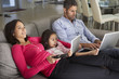 © Monkey Business - Family On Sofa With Laptop And Digital Tablet Watching TV
