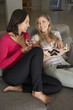 © Monkey Business - Two Women Sitting On Sofa Watching TV Drinking Wine
