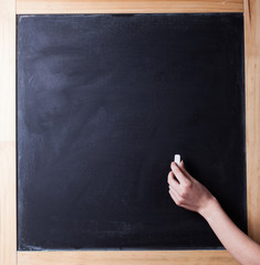 The human hand starts writing with chalk on a clean blackboard