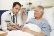 © Monkey Business - Doctor Sitting By Male Patient's Bed Using Digital Tablet