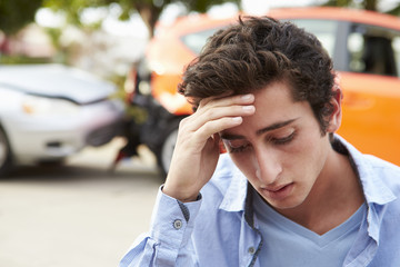 Worried Teenage Driver Sitting By Car After Traffic Accident