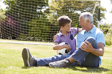 Canvas Print - Grandfather And Grandson Playing Football In Garden