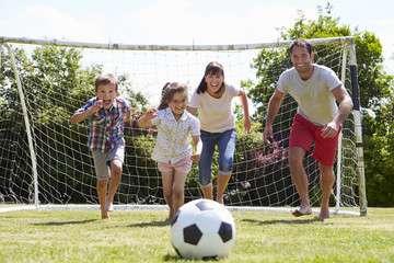 Wall Mural - Family Playing Football In Garden Together