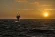 Caravel unmanned gas platform in rough seas silhouetted against