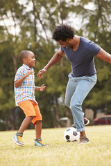 Father With Son Playing Soccer In Park Together