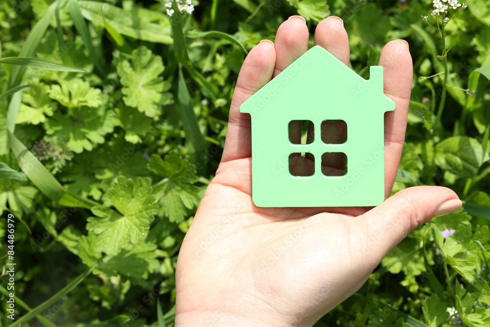 Female hand holding toy house outdoors