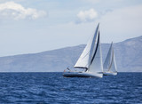Fototapeta  - Sailing in the wind through the waves at the Aegean Sea. 