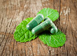 © showcake - Organic capsule with mint leaves on wood