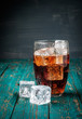 Glass of cola with ice on a wooden table.