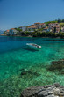 Speedboat moored in turquiose bay in Kephalonia with houses on t