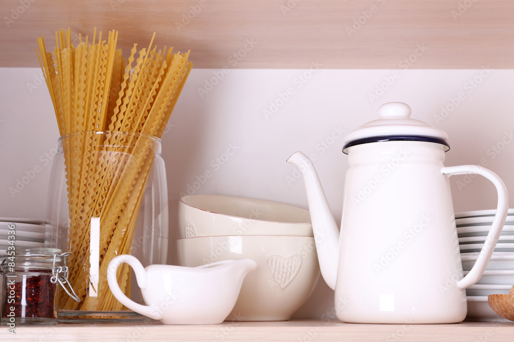 Kitchen utensils and tableware on wooden shelf