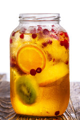 Wall Mural - Glass jar of homemade spritzer (schorle) with carbonated apple juice served with frozen fruit wheels, ice cubes and wild cranberry