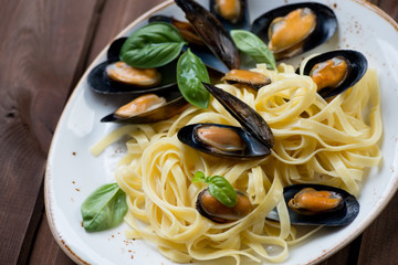 Wall Mural - Boiled mussels with tagliatelle and basil on a plate, close-up