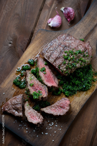 Medium rare beef steak with chimichurri on a cutting board Tablou Canvas