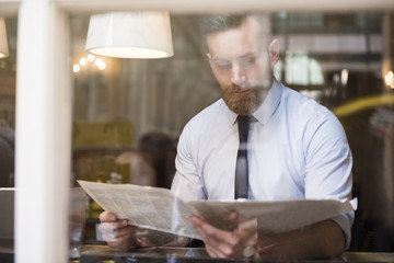 Young businessman reading newspaper