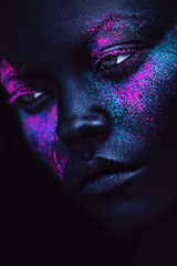 portrait of woman in black paint and neon powder