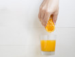 Man hand squeezing orange  on orange juice glass