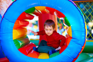 Wall Mural - cute happy kid, boy playing in inflatable attraction on playground