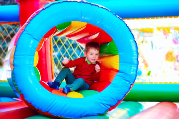 Wall Mural - cute happy kid, boy playing in inflatable attraction on playground